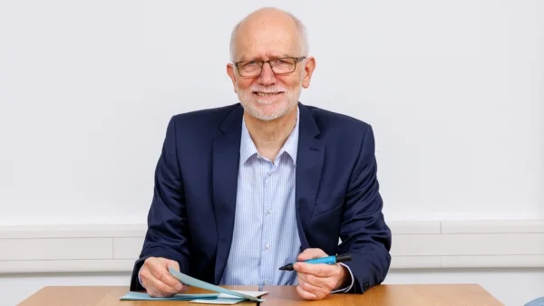 Porträt eines lächelnden Beraters im Anzug im Büro - Jürgen Rüst der als Ansprechpartner für Beratung und Fragen zur Verfügung steht.